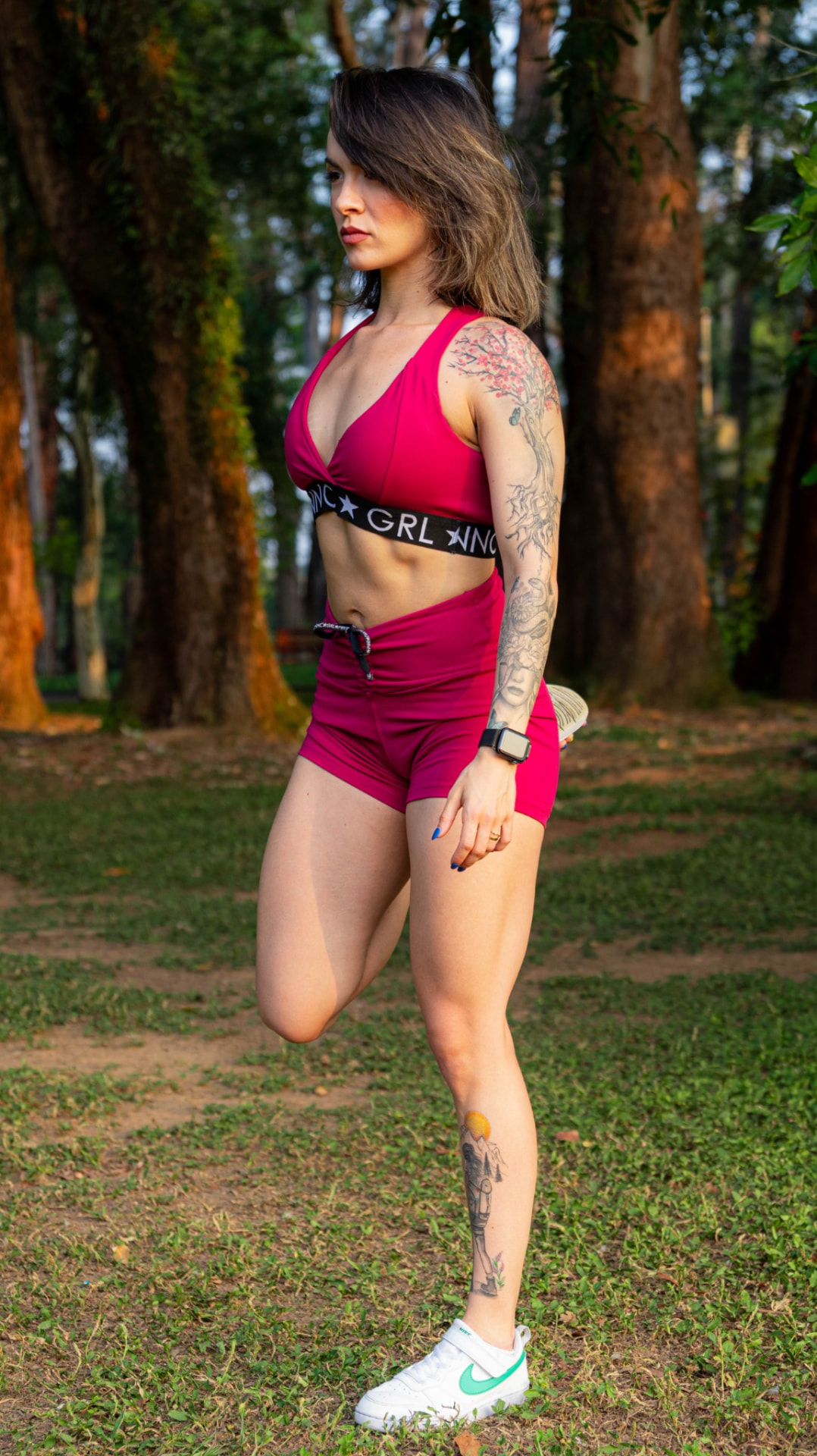 Debora Aguirre in a standing stretch outdoors among the trees